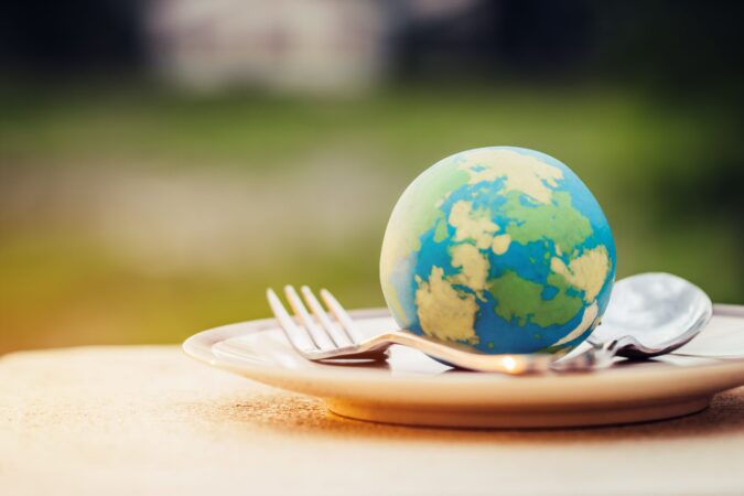 Globe model placed on plate with fork spoon for serve menu in famous hotels. International cuisine is practiced around the world often associated with specific region country. World food inter concept